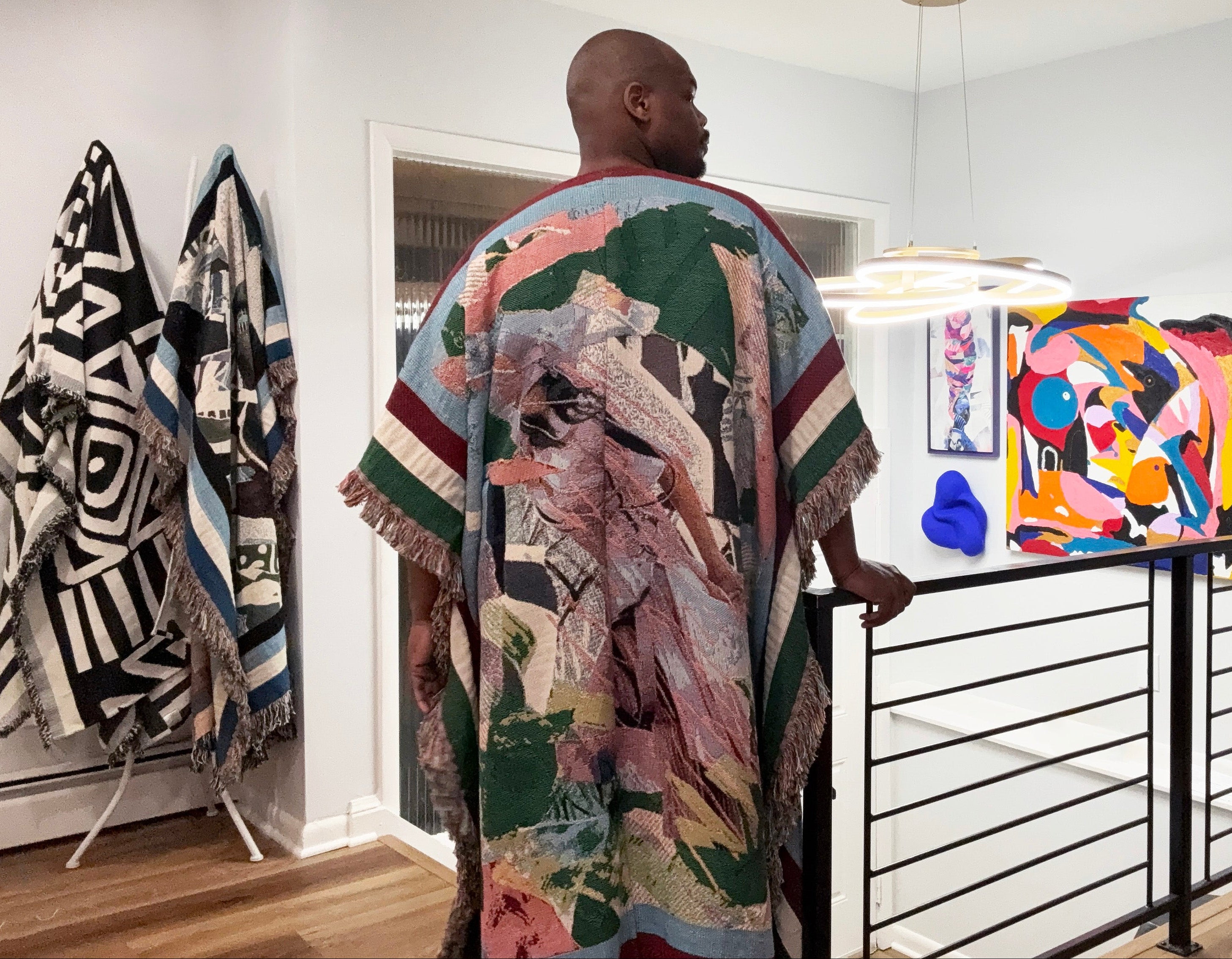 Man wearing a colorful patterned robe in a modern interior setting with art on the wall.